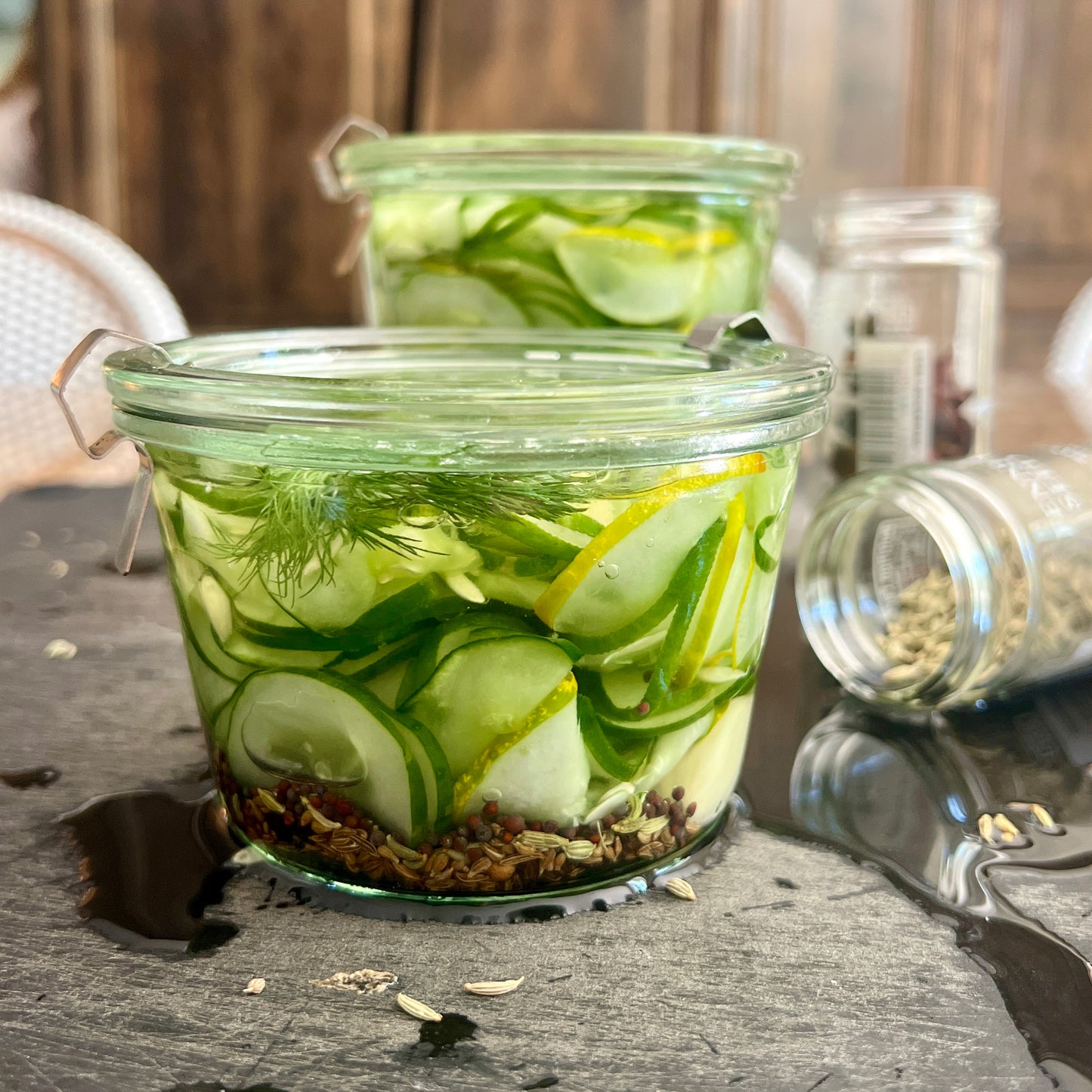 Two jars of pickles n canning jars on a black cutting board.