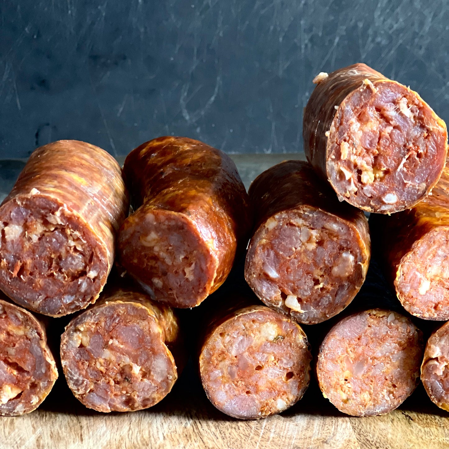 Andouille sausages stacked on top of each other like cigars with their ends cuts up to show fat, pork and spice cross cut.