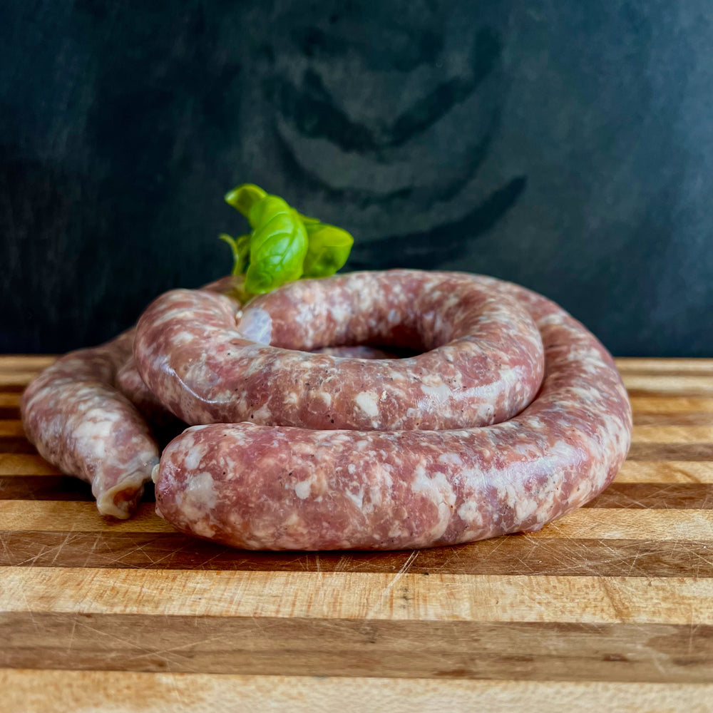 A coil of fresh Toulouse  sausage on a wooden cutting and slate background. 